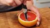
                    Le couteau à pamplemousse coupant un grapefruit