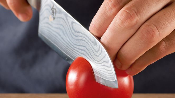 
                    Couteau Santoku en coupant une tomate