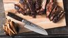 
                    Le couteau Kai Santoku avec de la viande